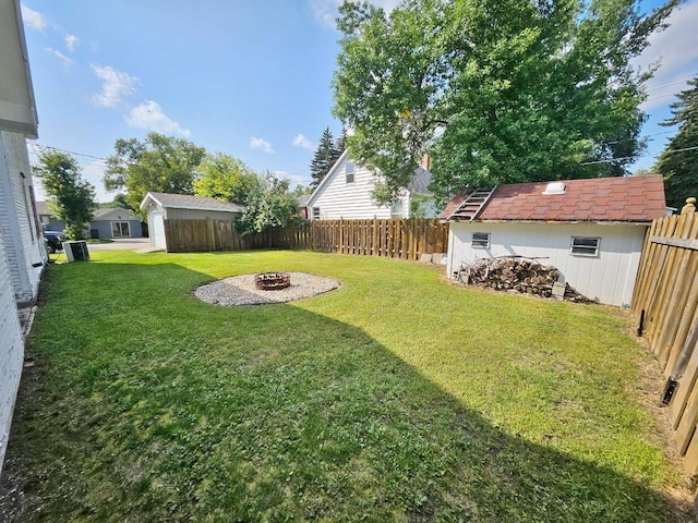 401 5th St, Rugby, ND 58368 - view of yard featuring an outdoor structure, a fenced backyard, a fire pit, and a storage shed