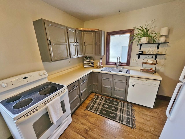 401 5th St, Rugby, ND 58368 - kitchen with gray cabinets, a sink, light countertops, white appliances, and light wood-style flooring