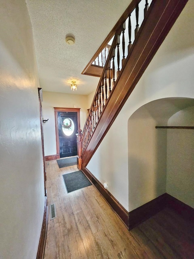 foyer entrance with a textured ceiling and wood-type flooring