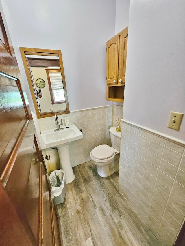 bathroom featuring hardwood / wood-style flooring, toilet, and tile walls