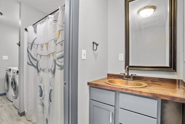 bathroom with washing machine and clothes dryer, wood-type flooring, and vanity