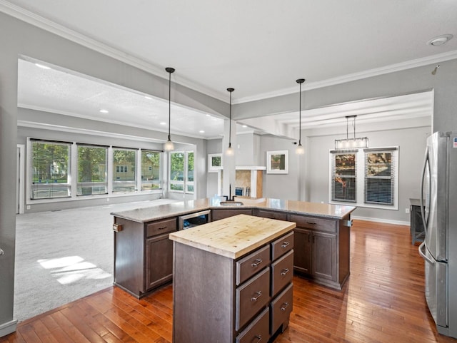 kitchen with open floor plan, hanging light fixtures, freestanding refrigerator, and a center island