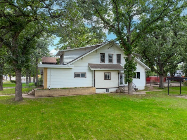 rear view of house with entry steps, a lawn, and a chimney