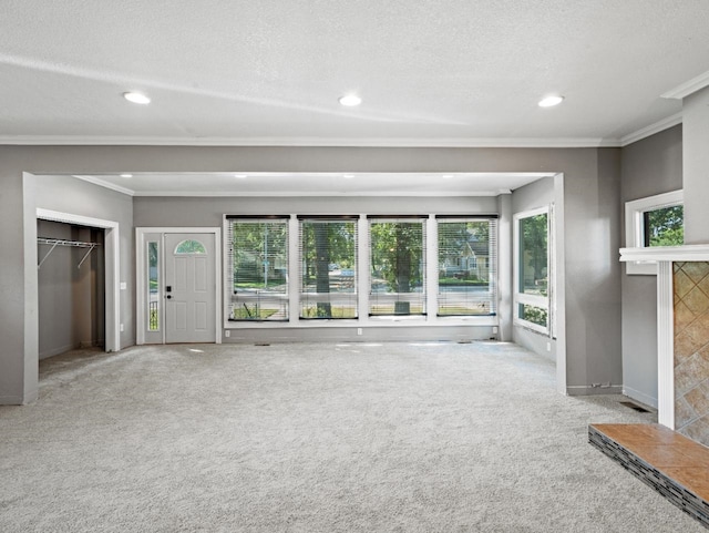 unfurnished living room with a tile fireplace, light colored carpet, crown molding, and recessed lighting