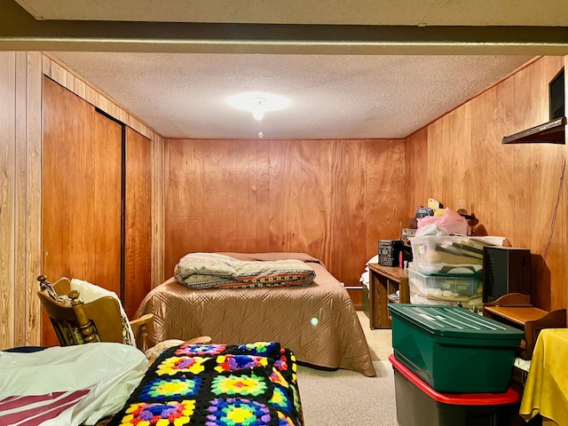 bedroom featuring a textured ceiling, carpet flooring, wood walls, and a closet