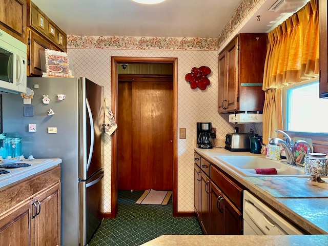 kitchen featuring white appliances, dark tile patterned floors, and sink