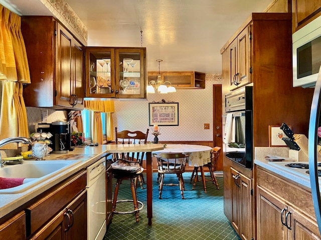 kitchen with hanging light fixtures, an inviting chandelier, white appliances, sink, and decorative backsplash