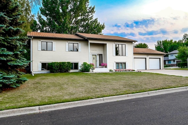 raised ranch featuring an attached garage, driveway, and a front yard