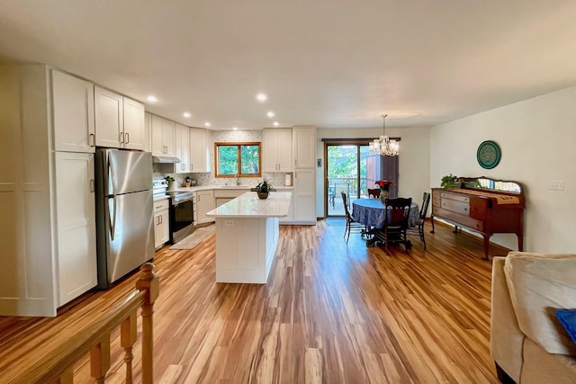 kitchen with light wood-type flooring, tasteful backsplash, white cabinetry, appliances with stainless steel finishes, and light countertops