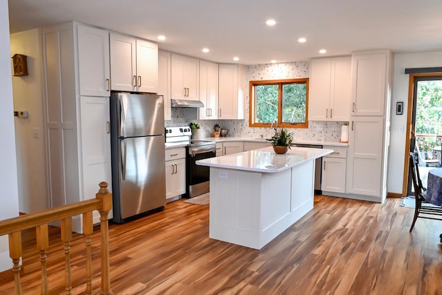 kitchen with light countertops, a healthy amount of sunlight, under cabinet range hood, and stainless steel appliances