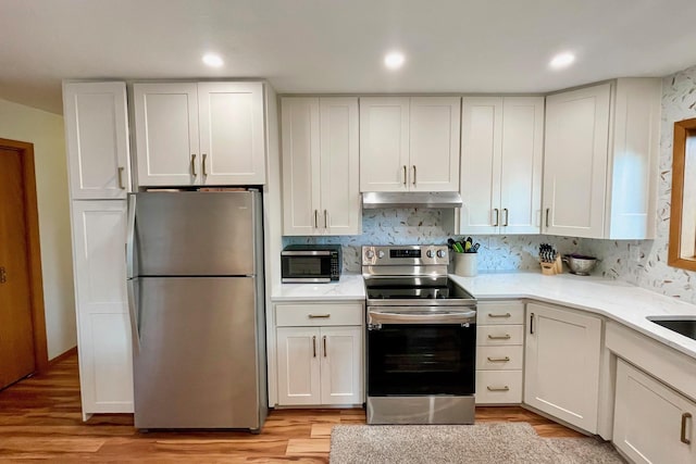 kitchen featuring under cabinet range hood, appliances with stainless steel finishes, white cabinetry, and light wood-type flooring