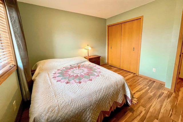 bedroom featuring light wood-type flooring, baseboards, and a closet