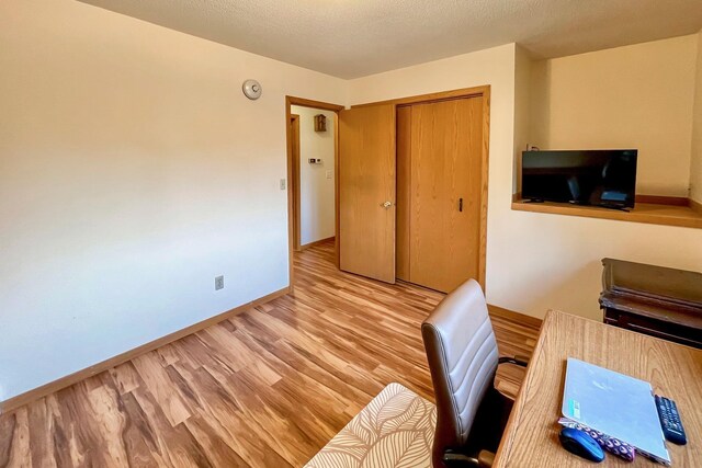 office featuring a textured ceiling, baseboards, and wood finished floors