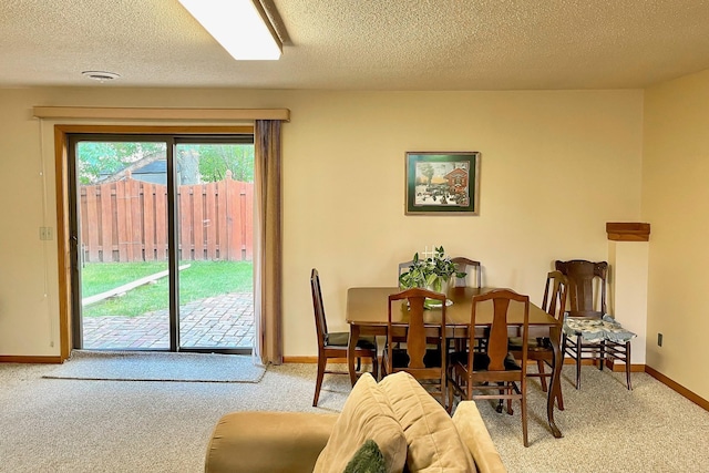 dining space featuring baseboards, carpet floors, and a textured ceiling