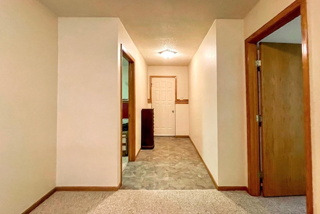 corridor featuring baseboards and carpet floors