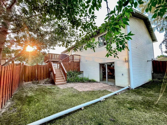 rear view of property featuring a yard, stairway, a wooden deck, and a fenced backyard