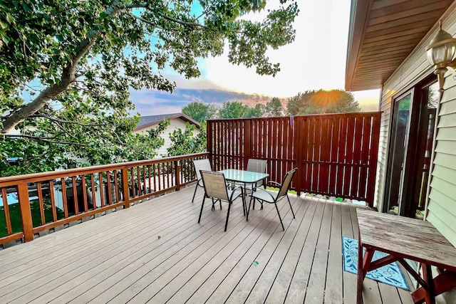 deck at dusk featuring outdoor dining space