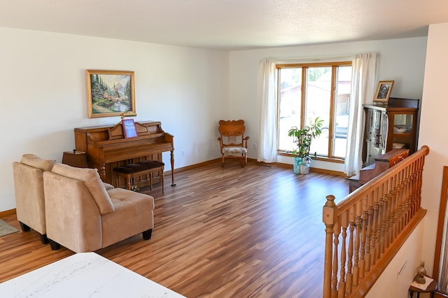 sitting room featuring an upstairs landing, baseboards, and wood finished floors