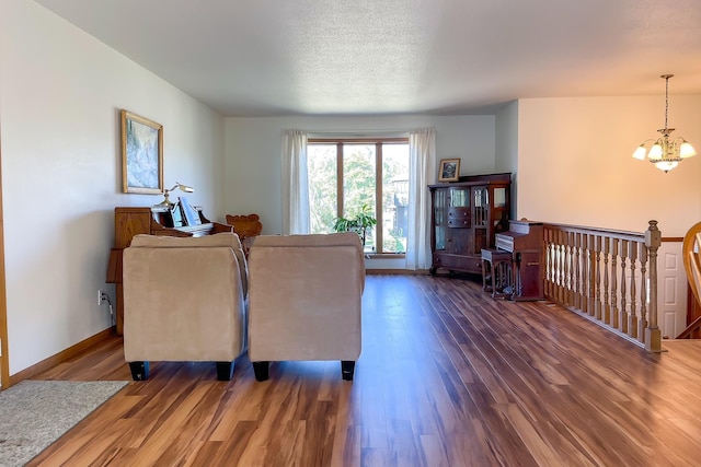 living area with baseboards, a notable chandelier, wood finished floors, and a textured ceiling