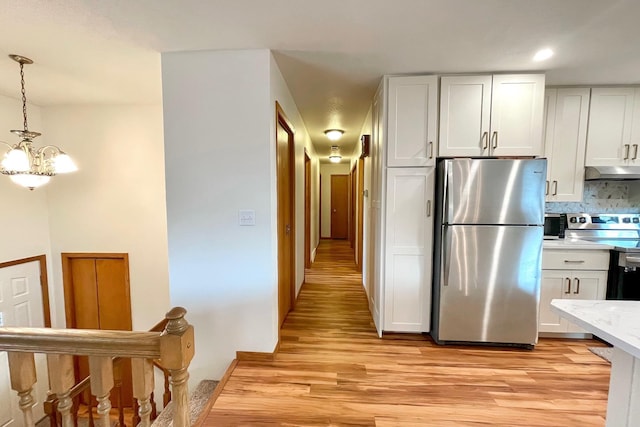 kitchen with under cabinet range hood, white cabinets, stainless steel appliances, and light wood-type flooring