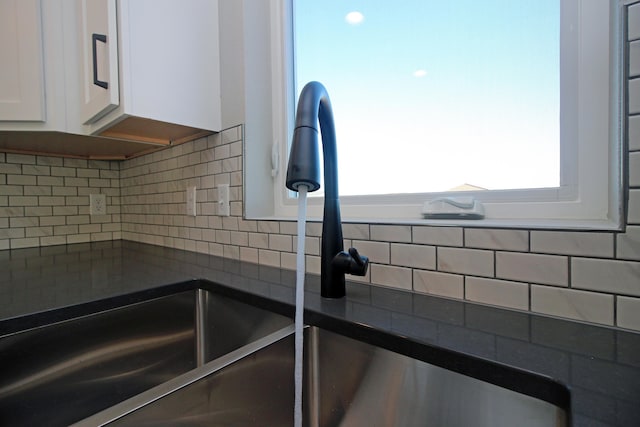 room details featuring white cabinetry, backsplash, and sink