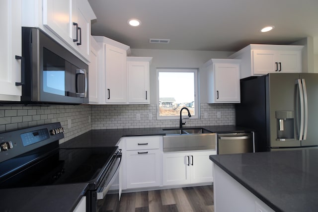 kitchen featuring tasteful backsplash, stainless steel appliances, wood-type flooring, sink, and white cabinets