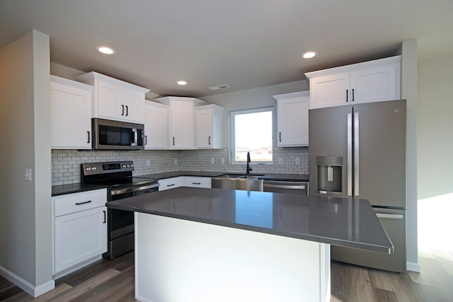 kitchen featuring a kitchen island, hardwood / wood-style flooring, appliances with stainless steel finishes, and white cabinets