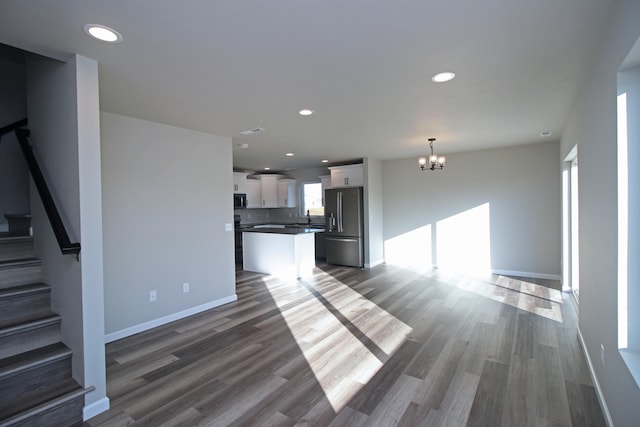 unfurnished living room with hardwood / wood-style flooring, an inviting chandelier, and sink