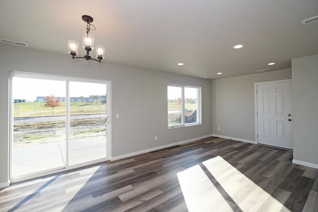 spare room with a notable chandelier and dark hardwood / wood-style floors