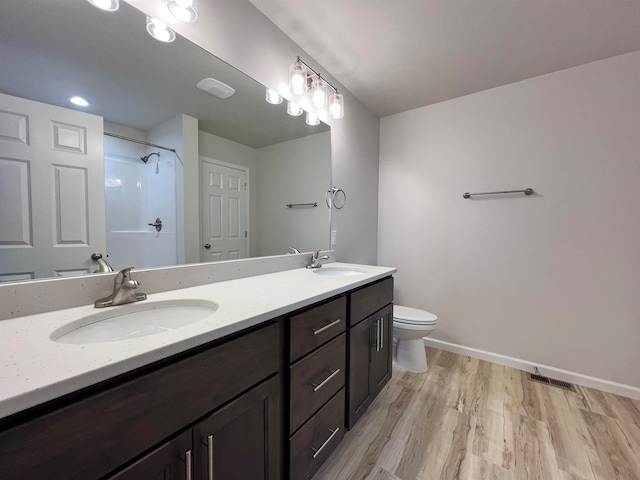 bathroom with vanity, toilet, hardwood / wood-style floors, and a shower