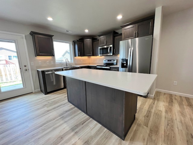 kitchen with light hardwood / wood-style flooring, stainless steel appliances, a center island, sink, and dark brown cabinetry