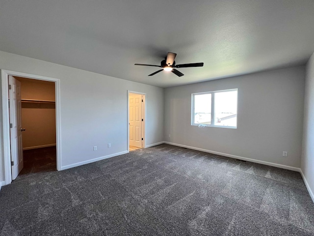 unfurnished bedroom featuring a walk in closet, ceiling fan, and carpet floors