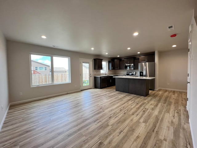 kitchen featuring light wood-type flooring, stainless steel appliances, sink, dark brown cabinets, and a kitchen island