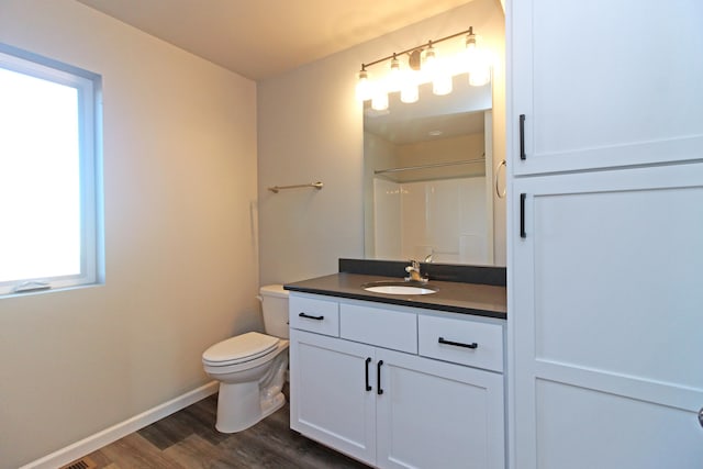 bathroom featuring wood-type flooring, toilet, walk in shower, and vanity