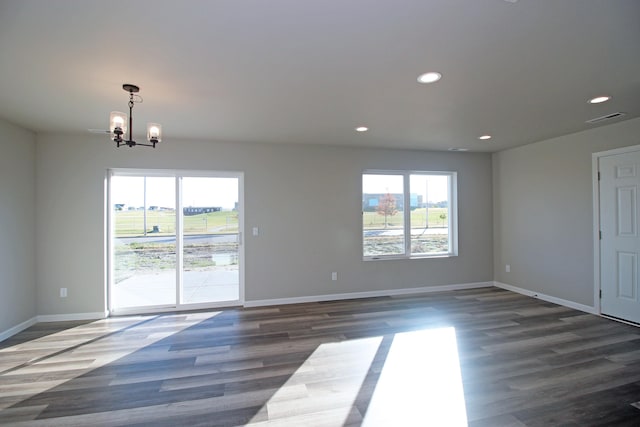 empty room featuring dark wood-type flooring and a chandelier