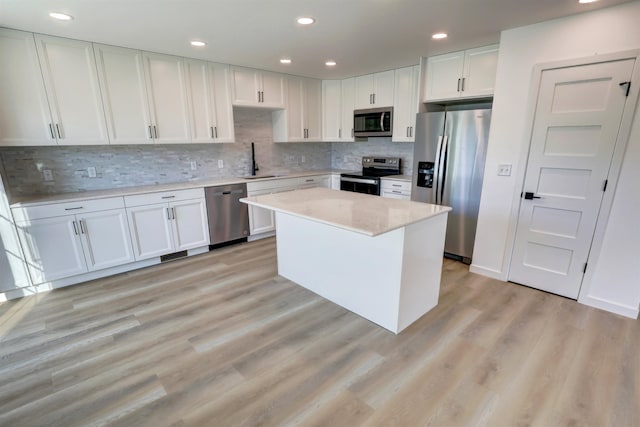 kitchen featuring light hardwood / wood-style floors, a center island, stainless steel appliances, sink, and white cabinets