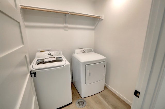 laundry room with washing machine and clothes dryer and light hardwood / wood-style floors