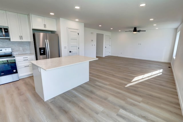 kitchen featuring appliances with stainless steel finishes, white cabinetry, light hardwood / wood-style flooring, and ceiling fan