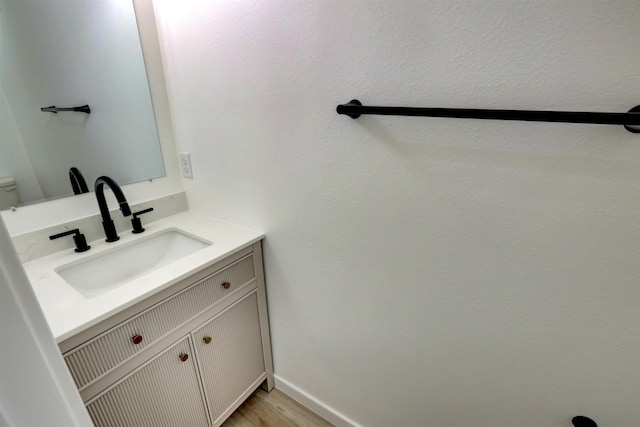 bathroom featuring wood-type flooring, toilet, and vanity