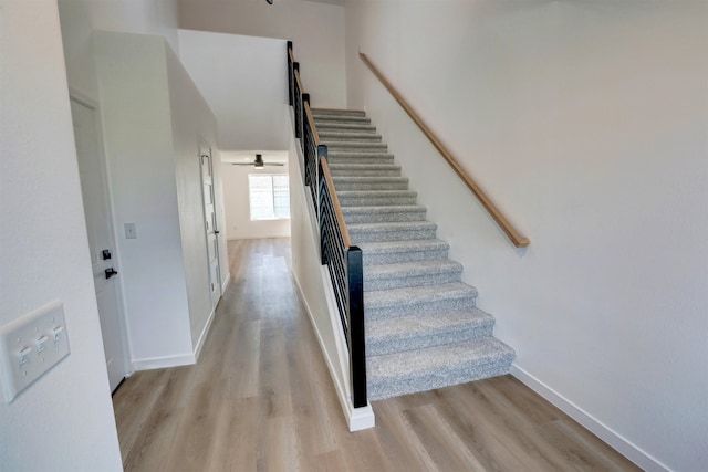 staircase with wood-type flooring and ceiling fan