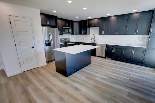 kitchen featuring light wood-type flooring, stainless steel appliances, sink, a kitchen island, and tasteful backsplash