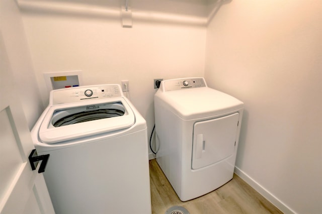 clothes washing area with separate washer and dryer and light wood-type flooring