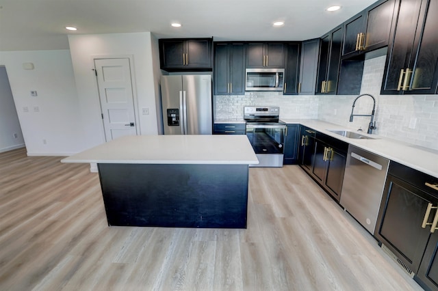 kitchen with light hardwood / wood-style flooring, appliances with stainless steel finishes, a kitchen island, and sink