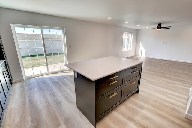 kitchen with a wealth of natural light, light hardwood / wood-style flooring, ceiling fan, and a center island