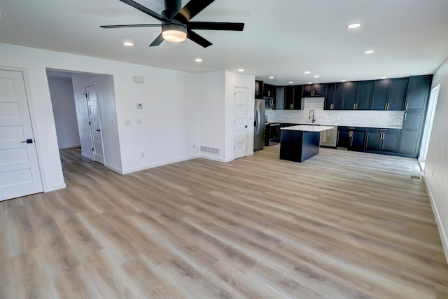 unfurnished living room with ceiling fan, sink, and light wood-type flooring