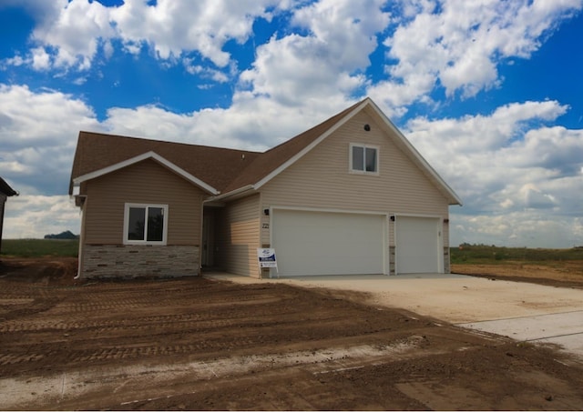 view of front of home featuring driveway, stone siding, and a garage