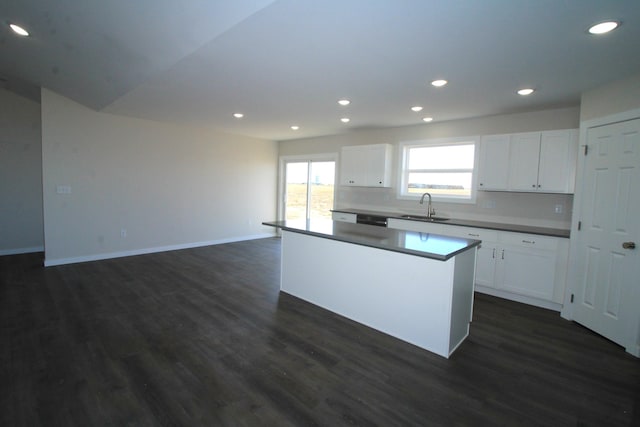 kitchen with a kitchen island, sink, white cabinets, and dark wood-type flooring