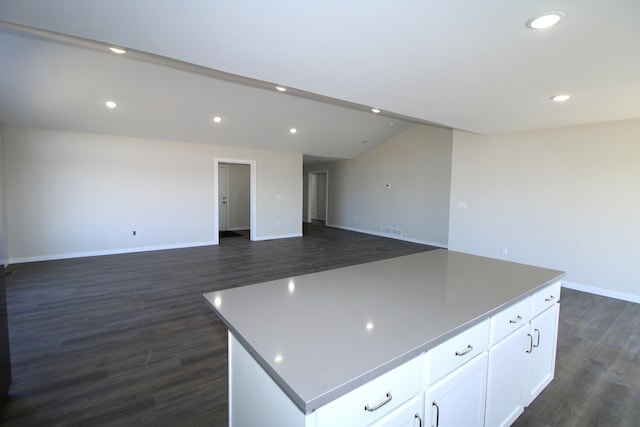 kitchen featuring dark wood-type flooring, lofted ceiling, a center island, and white cabinetry