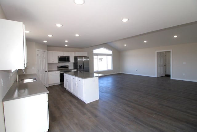 kitchen with a kitchen island, vaulted ceiling, stainless steel appliances, sink, and white cabinets