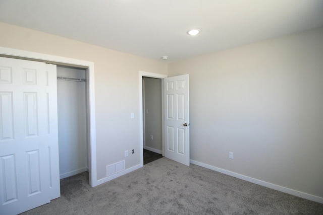 unfurnished bedroom featuring light colored carpet and a closet